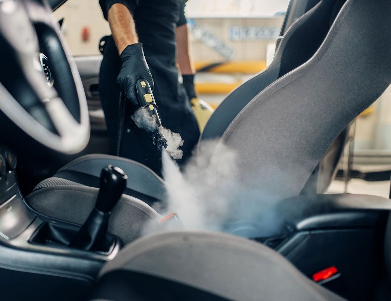 Ein Mann reinigt das Innere eines Autos mit Dampf, um Schmutz und Flecken effektiv zu entfernen