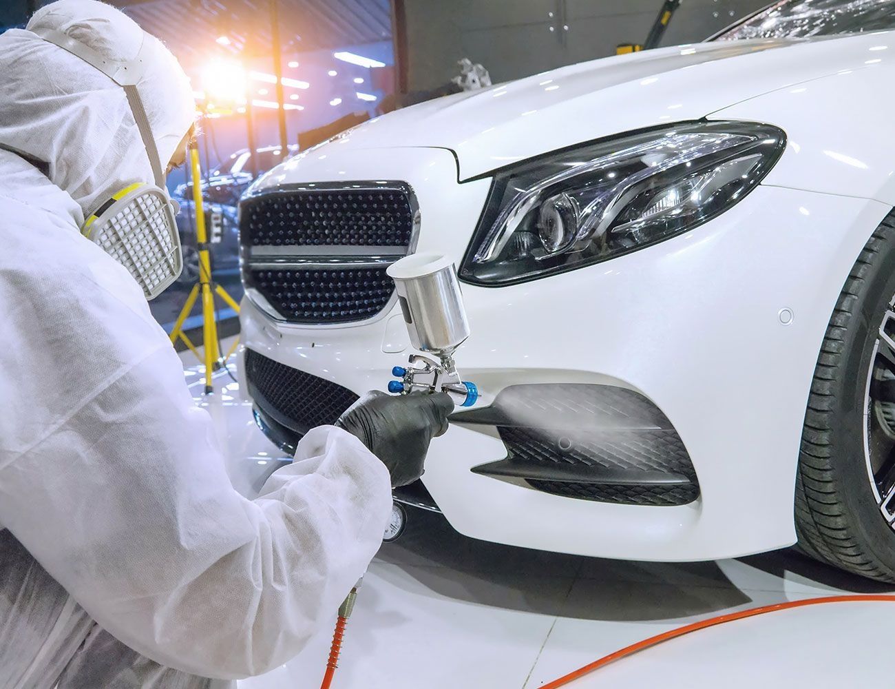 Eine Person im Anzug lackiert ein Auto