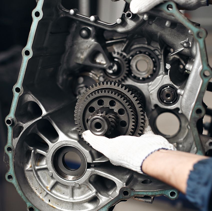 Eine Person steht vor einem Auto und arbeitet an dessen Motor, um technische Probleme zu beheben