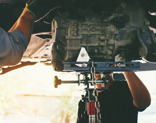 Zwei Männer sind mit der Wartung eines Autos beschäftigt und bauen einen Motor ein