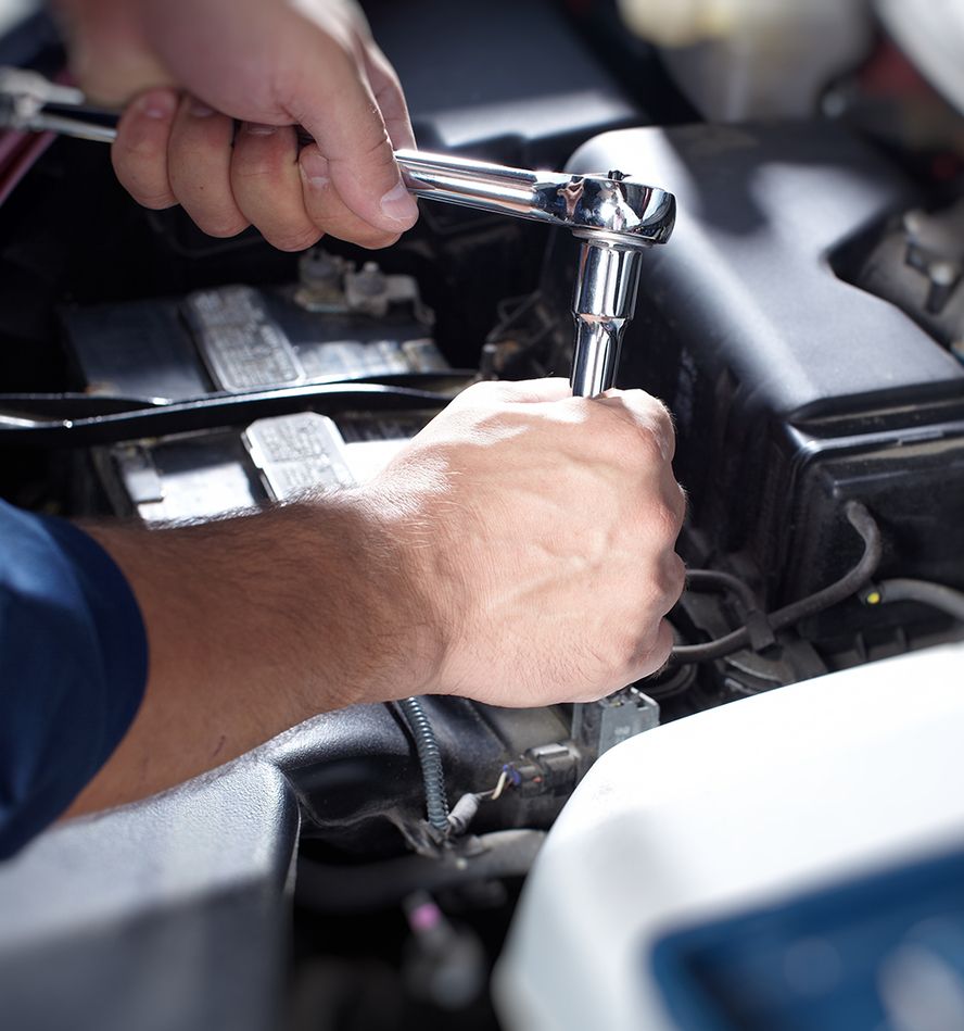 Ein Mann repariert einen Auto-Motor mit einem Schraubenschlüssel und zeigt dabei handwerkliches Geschick und Präzision